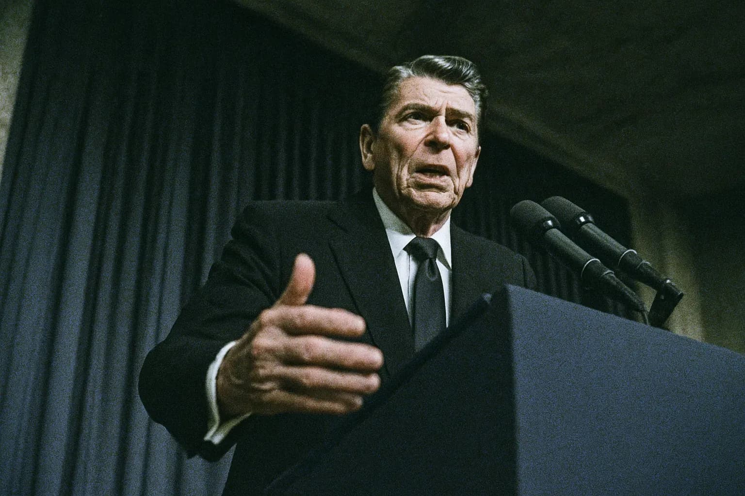 A figure resembling Ronald Reagan stands behind a podium, mid-speech, amid an air of tension and seriousness, conveying the weight of the Iran-Contra affair.