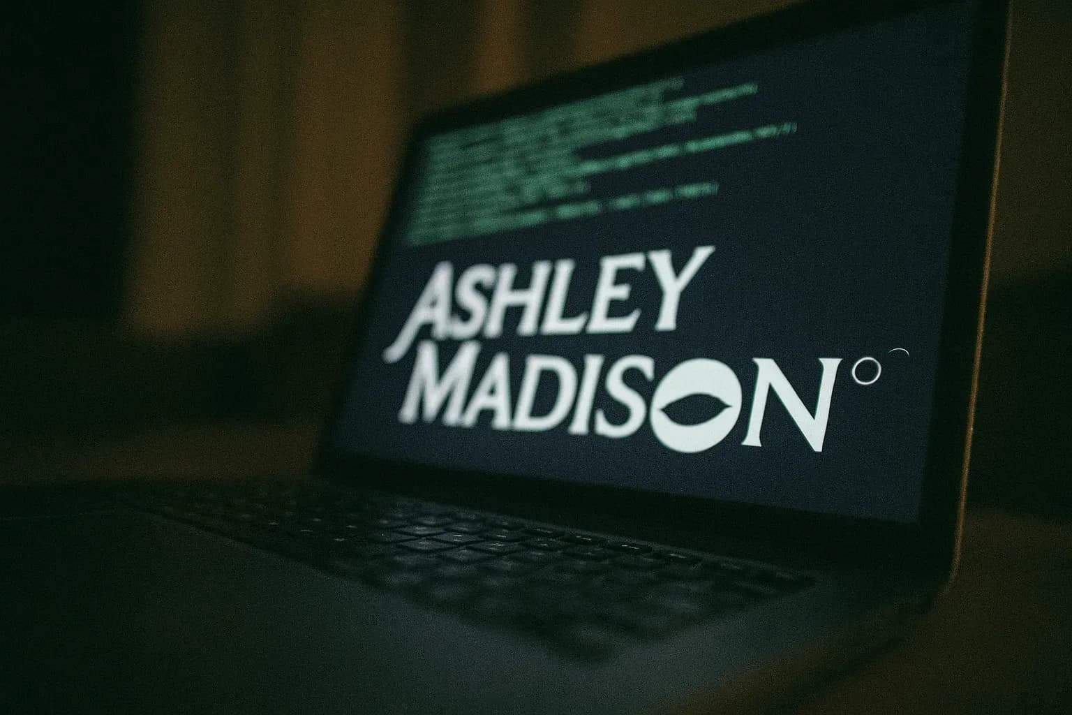 A laptop screen displaying the Ashley Madison logo amidst lines of code, symbolizing the 2015 data breach that exposed millions of users and led to global blackmail and personal tragedies